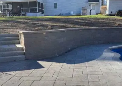 Patio with concrete floors and swimming pool by Modena NH hardscapes hudson nh
