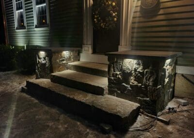 Masonry steps and pillars outside a house at night - hardscapes brookline nh