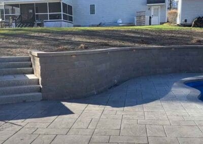 Patio with concrete floors and swimming pool by Modena NH hardscapes hudson nh